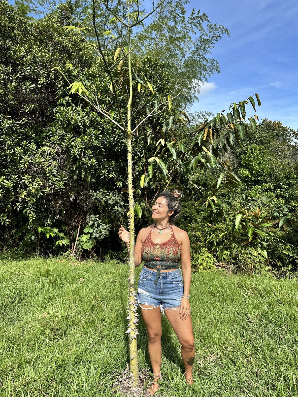 Olga de pie, sonriendo, junto al árbol que sembró para su hijo en San Rafael